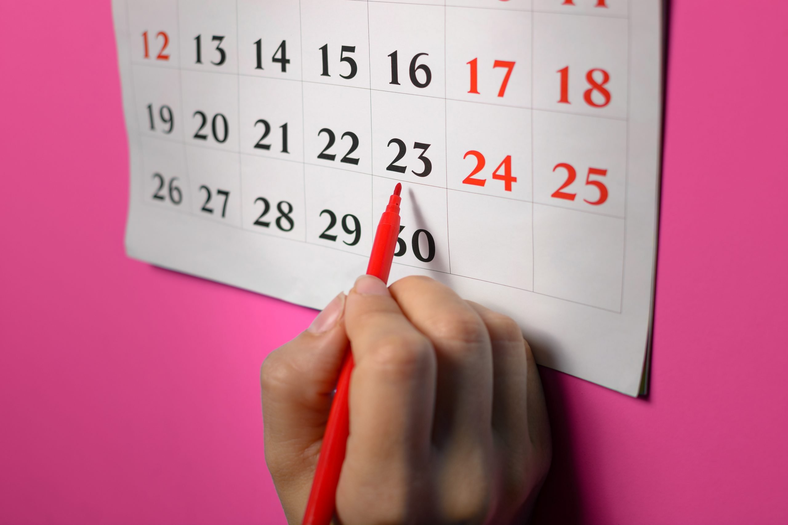 Female hand marks date of female cycle or ovulation  in the calendar