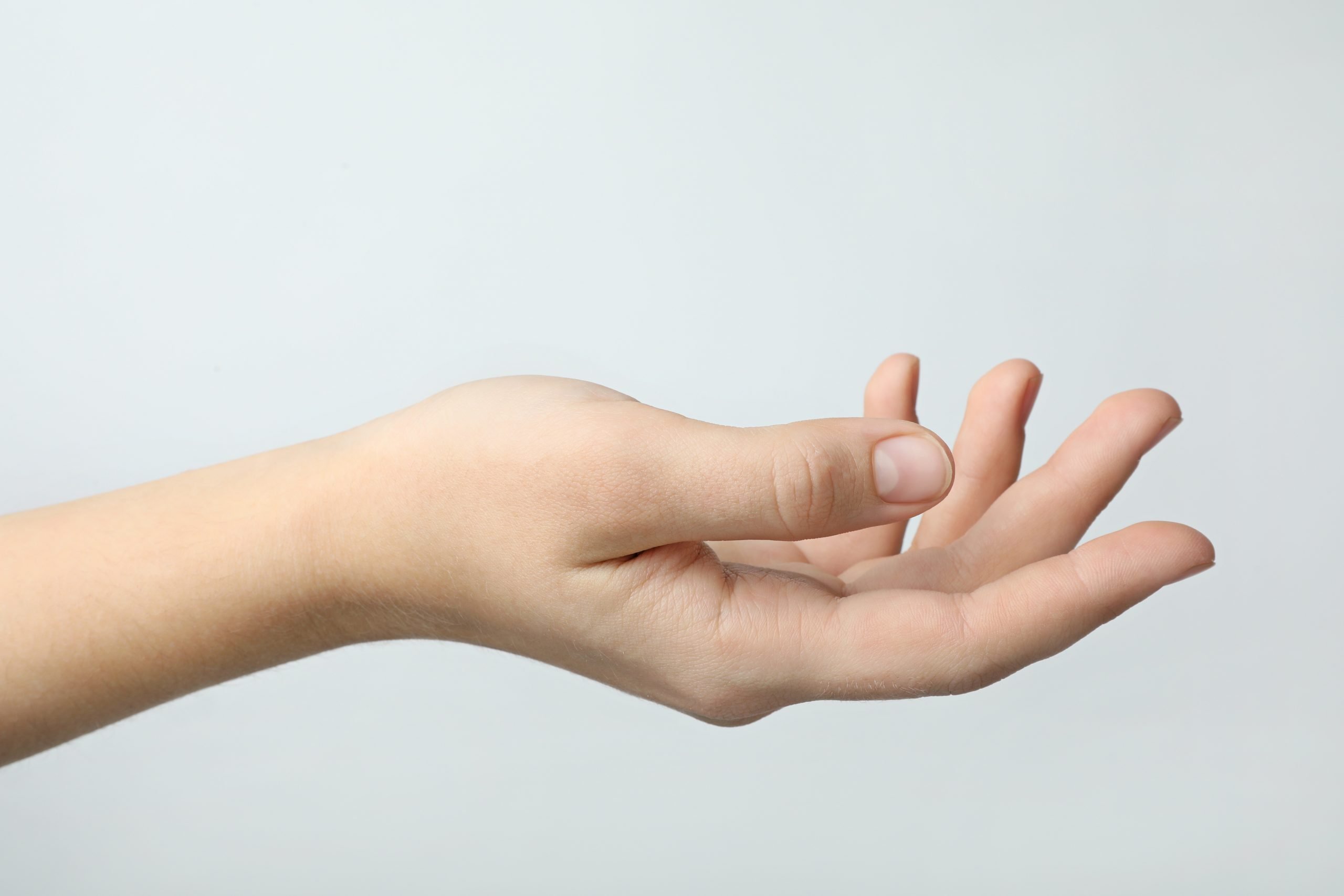 Woman holding something against light background, focus on hand